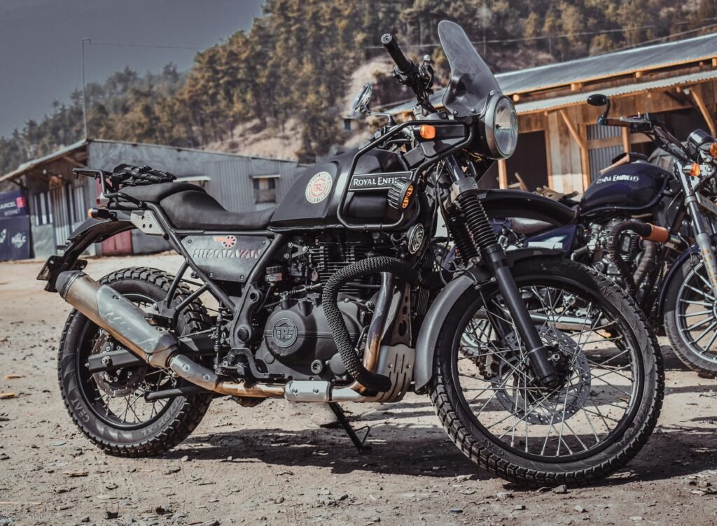 A Royal Enfield Himalayan motorbike parked outdoors in a rural Indian setting.